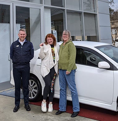 woman holding car keys in front of car with community members