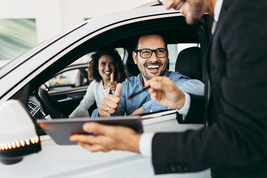 couple in car with salesman by car door
